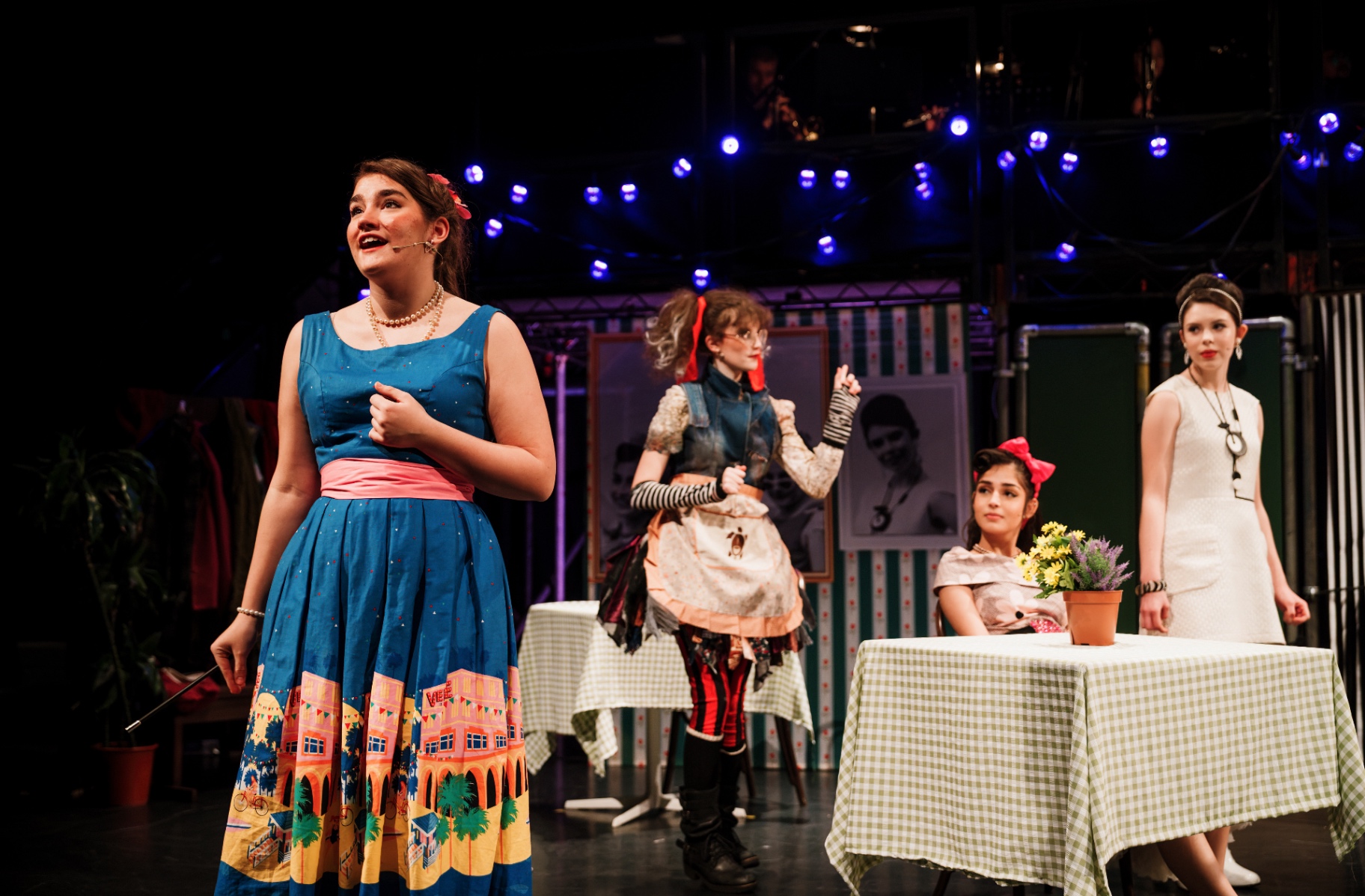A soloist sings in a blue dress before the portrait ghosts of the café.