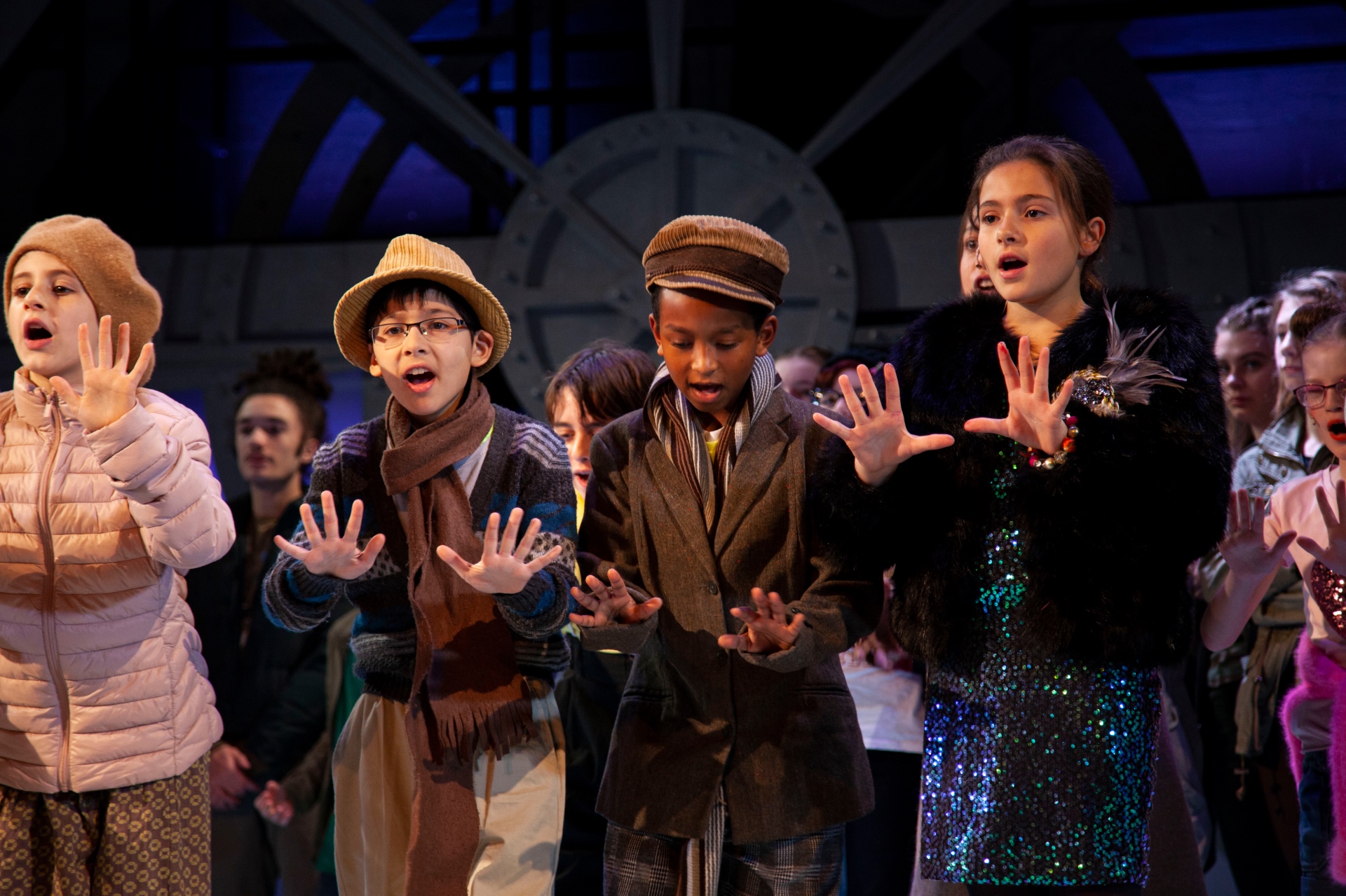 Young singers reaching towards the audience together during a London Youth Opera performance.